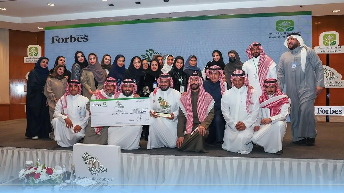 The CRS team with a trophy at the recognition ceremony, in front of Forbes Middle East and National Center for Responsibility and Studies branding.